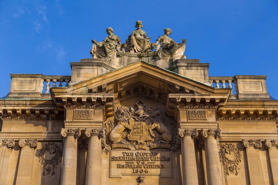 Un edifici majestuós amb escultures ornamentals i columnes, amb una inscripció destacada que commemora Sir William Henry Wills.
