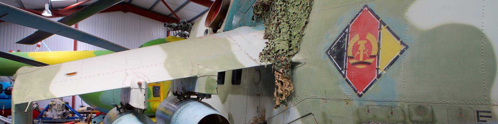 A military aircraft with camouflage paint, visible propellers, and a damaged fuselage.