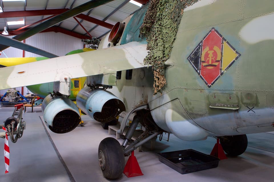A military aircraft with camouflage paint, visible propellers, and a damaged fuselage.