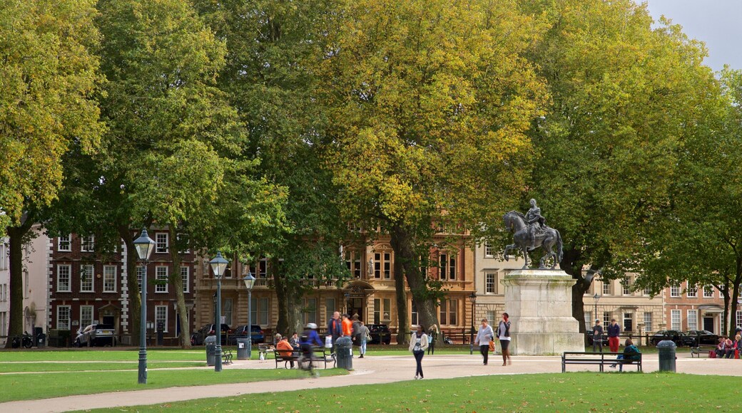 Queen Square which includes a garden and a statue or sculpture as well as a small group of people