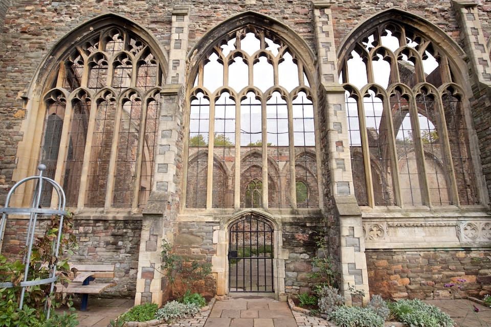 A historic stone building with large arched windows and a metal gate.