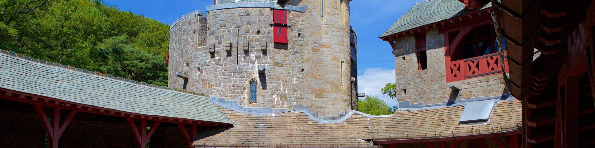 A medieval castle with stone walls, a tower, and a red-roofed building.