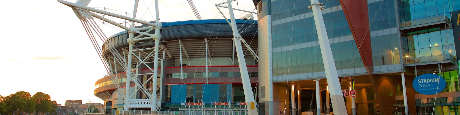 A modern stadium with a distinctive sail-like structure and a glass facade.
