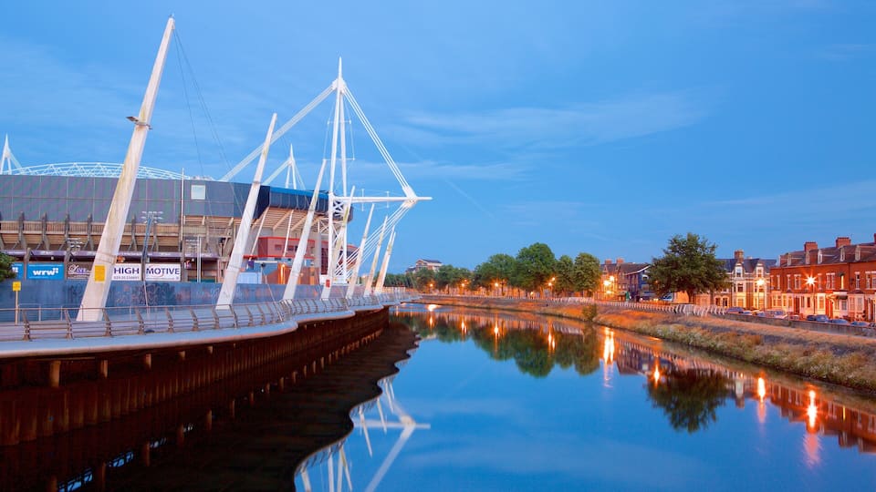 A river with a bridge and a stadium in the background.