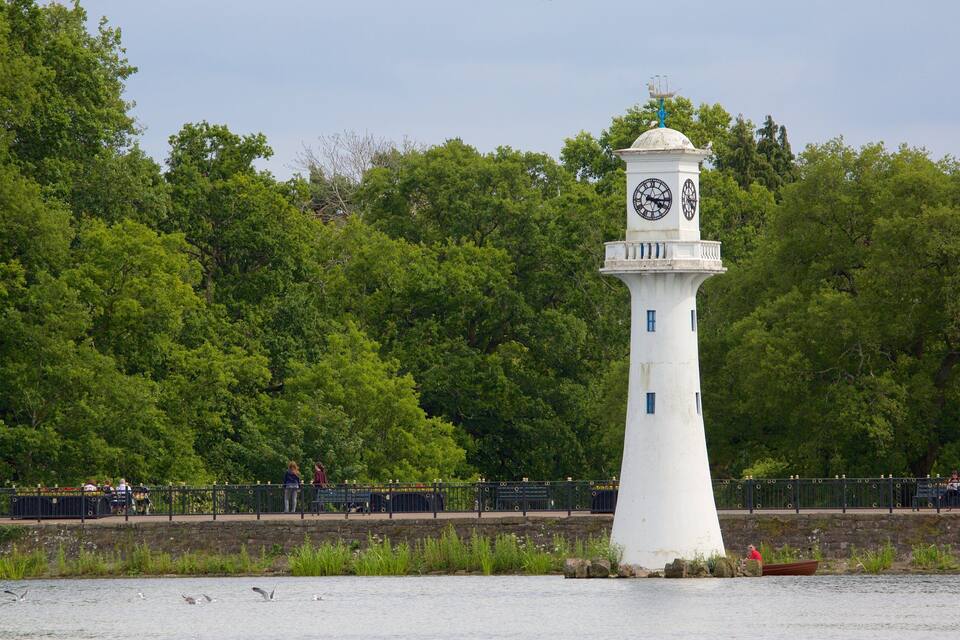 Ein weißer Leuchtturm mit einer Uhr auf seinem Turm, umgeben von üppigem Grün.