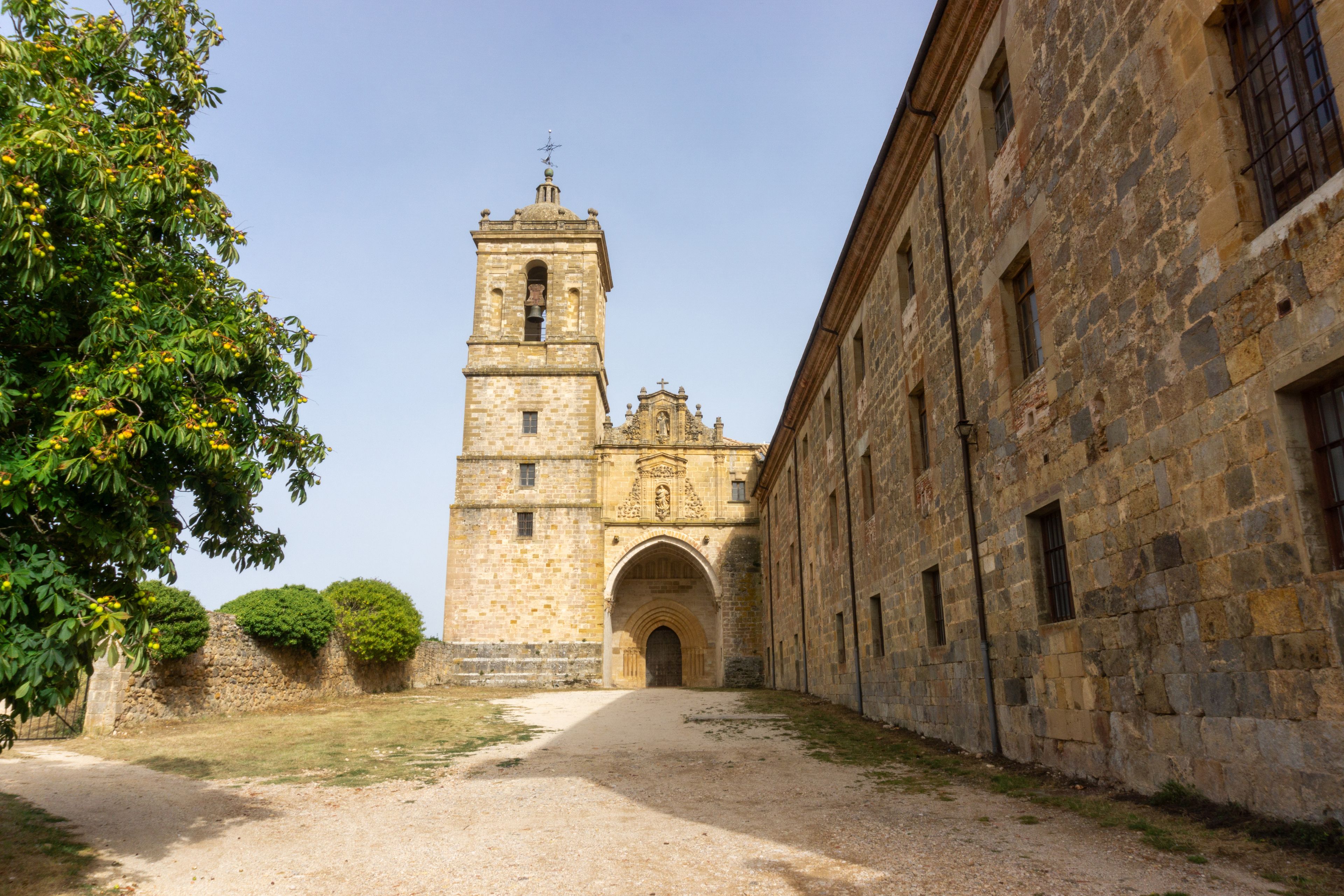 A historic stone building with a bell tower, an arched entrance, and a clear sky.