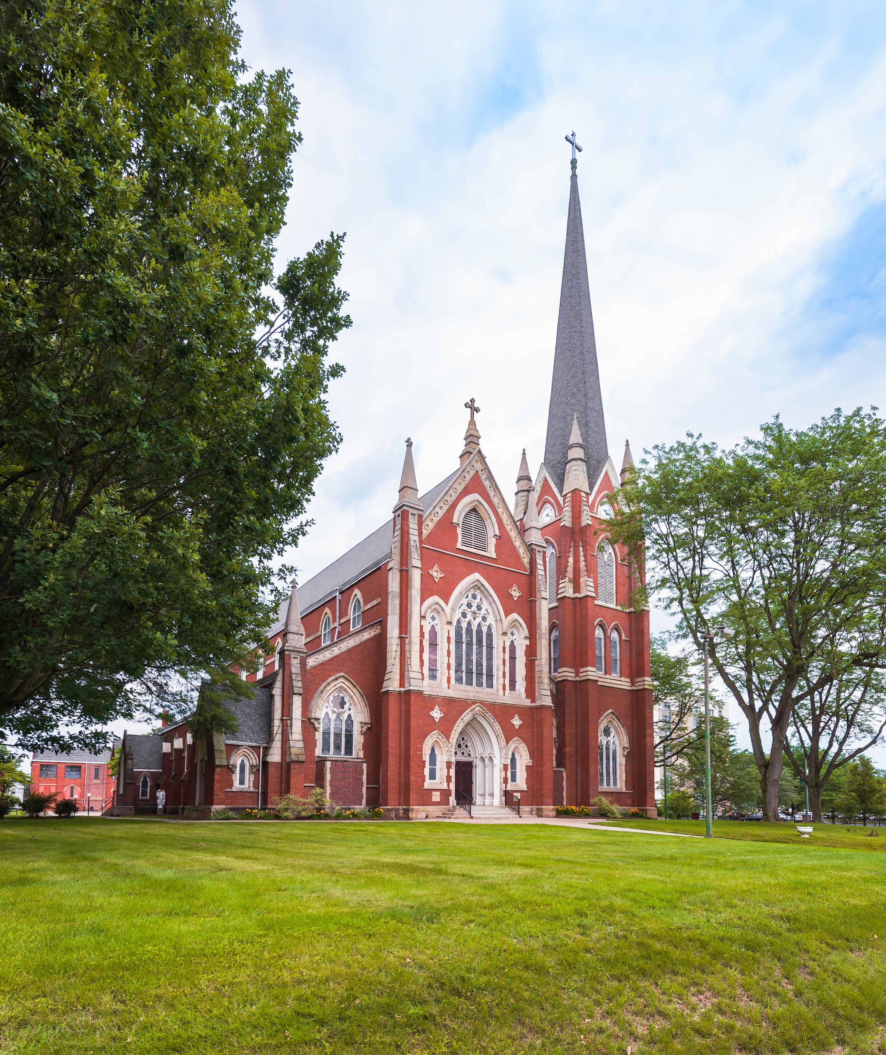 A large red brick church with a tall steeple and Gothic architecture.