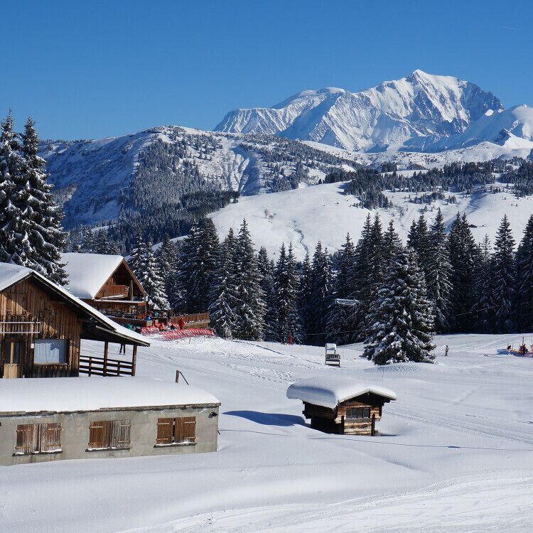 A snow-covered mountain landscape with wooden cabins and a ski lift.