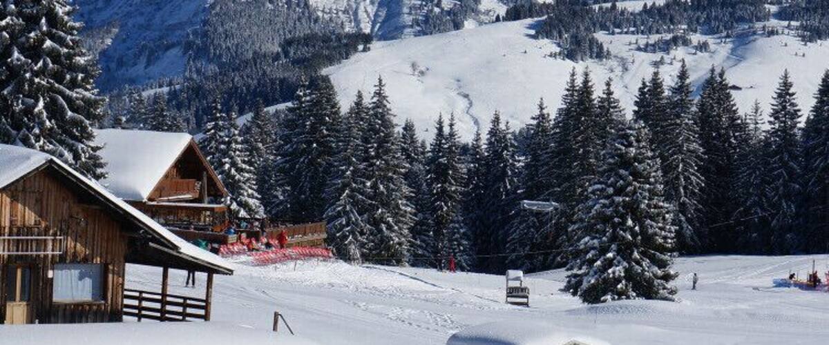A snow-covered mountain landscape with wooden cabins and a ski lift.