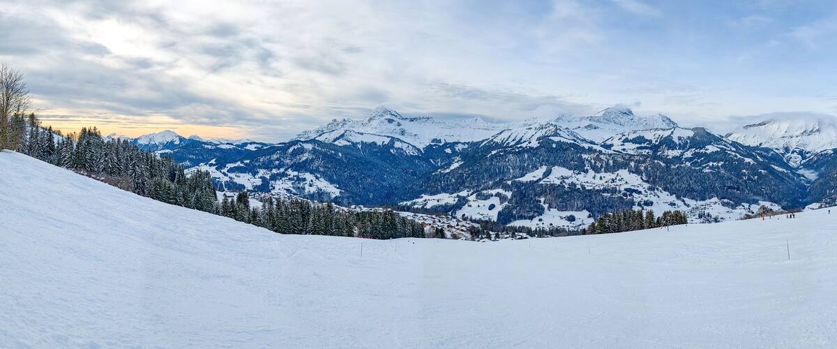 A snow-covered mountain range with clear skies and a ski slope.