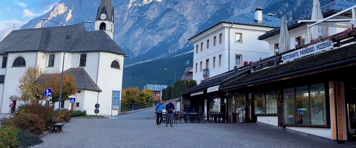 A town square with a church, a pizzeria, and a mountain in the background.