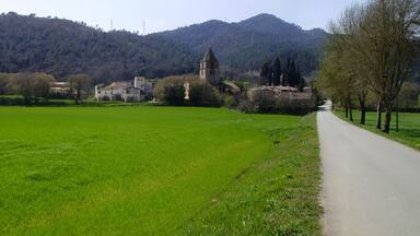 Paisaje rural con un campo verde, una carretera y una iglesia en una colina.