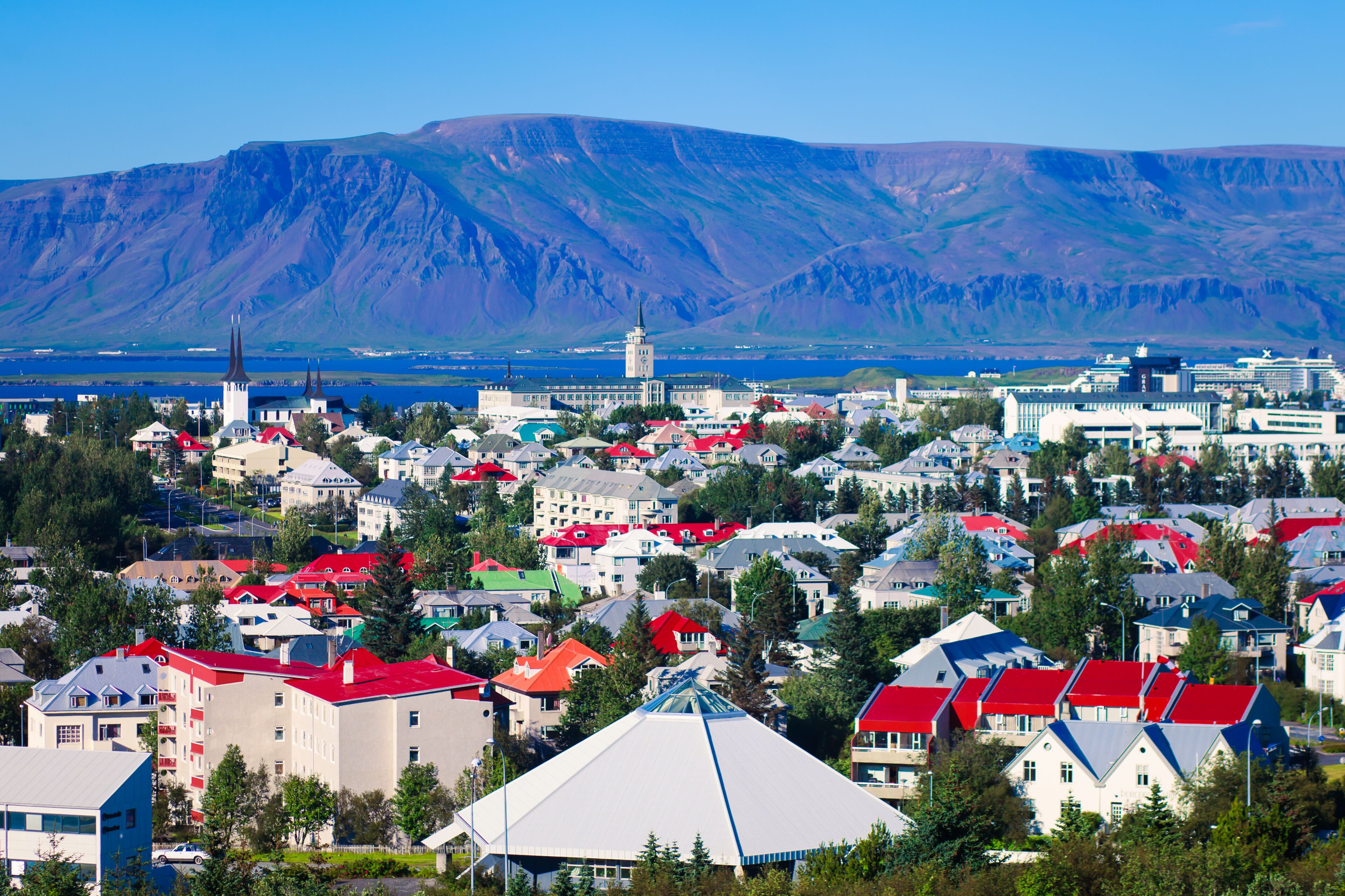 Beautiful super wide-angle aerial view of Reykjavik, Iceland with harbor and skyline mountains and scenery beyond the city, seen from the observation tower of Hallgrimskirkja Cathedral.
