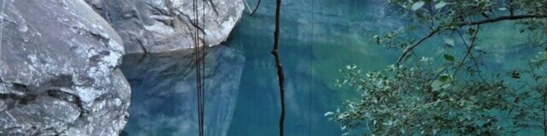 Piscina azul límpida rodeada por penhascos rochosos e árvores.