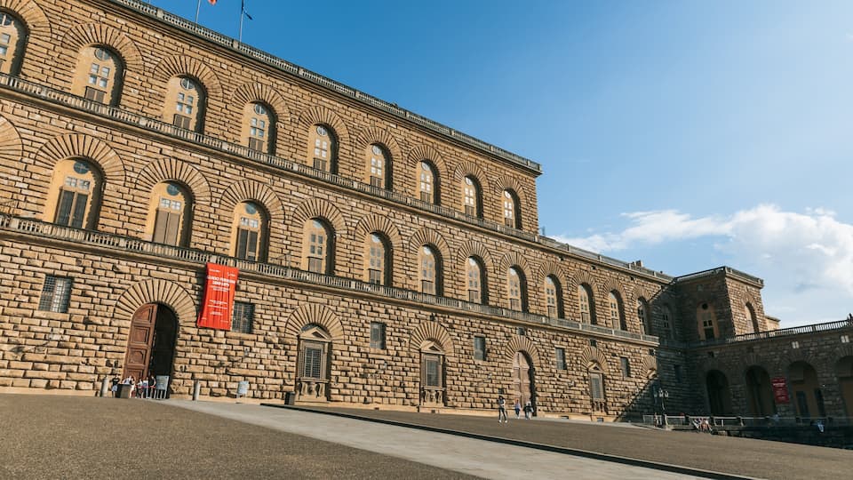 Un edifici de pedra gran amb finestres d'arc i un estendard vermell.