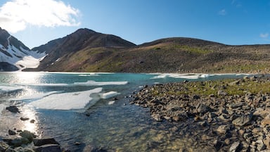 Panoramic shot of glacial lake in northern Canada during summer time on beautiful blue sky day. Large ice chunks in water, creek, river. Paddy Peak, Yukon Territory.