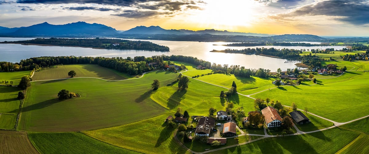 Un campo de golf con un lago, montañas y un atardecer.