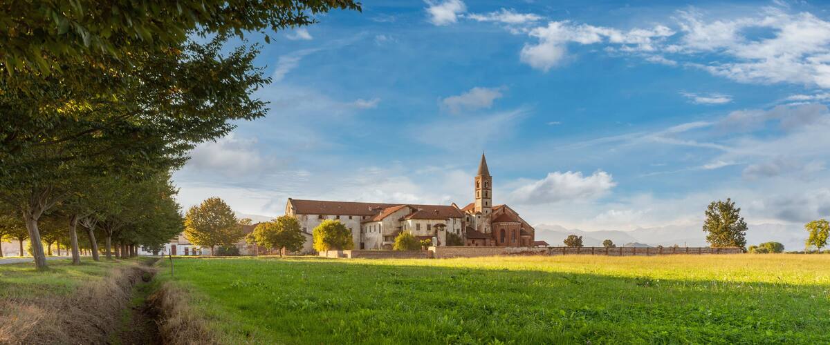 A church with a tall tower, surrounded by a grassy field and trees.