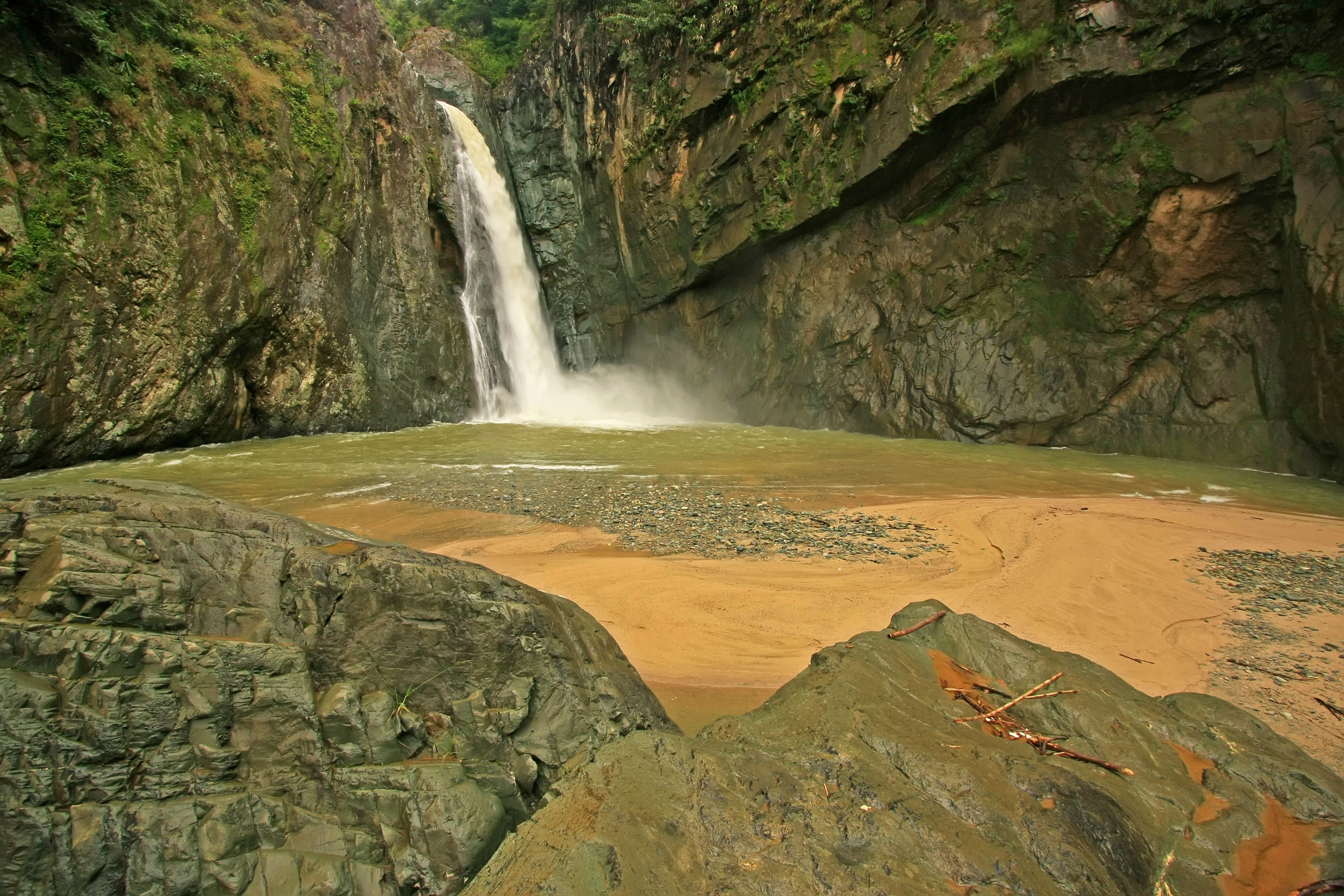 A waterfall cascading into a river surrounded by rocky cliffs.