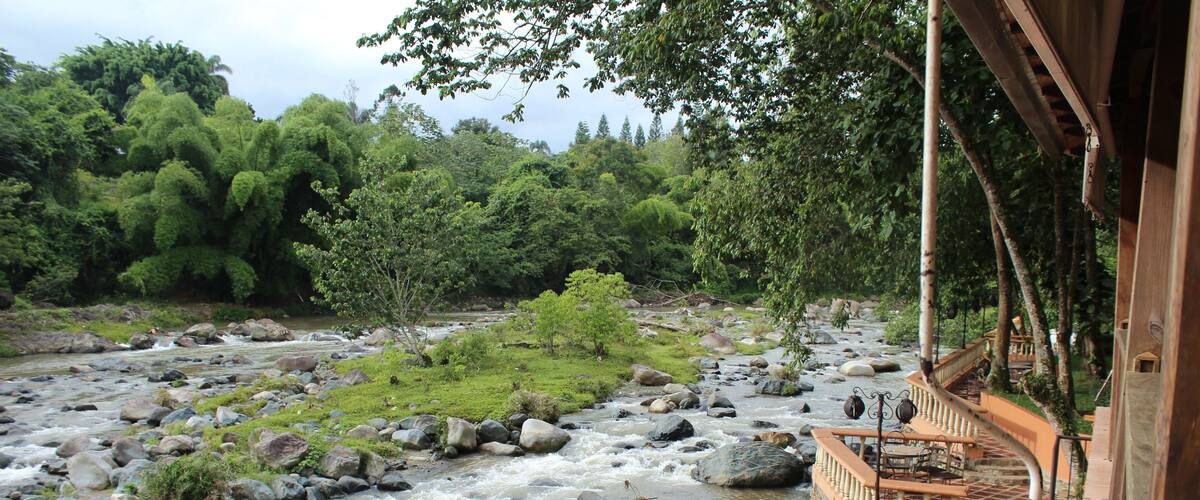 A river with rocks and a wooden bridge with a railing.