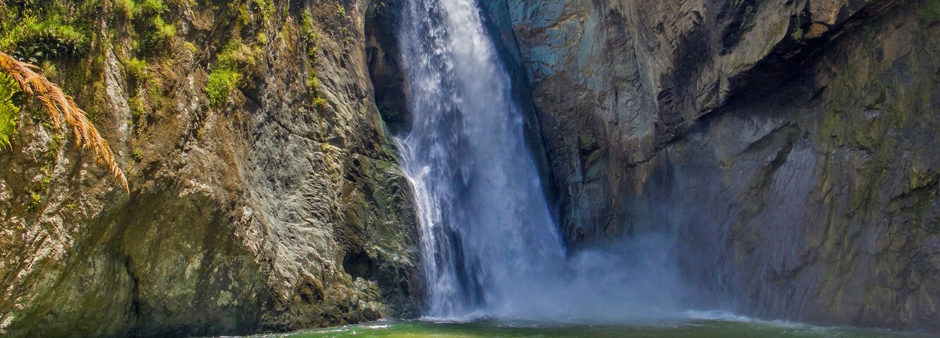 Una cascada que se precipita por un acantilado rocoso hacia un río.