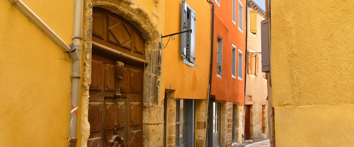 A narrow cobblestone street flanked by historic buildings with wooden doors and shutters.