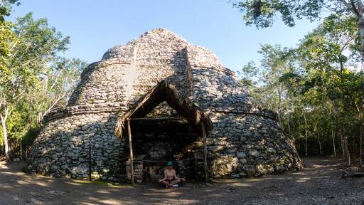 Young tourist doing yoga at a Mayan pyramid in Coba.