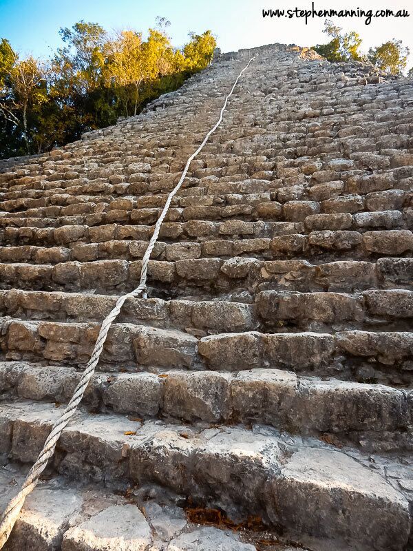 A stone staircase leading up a hill with a rope for support.