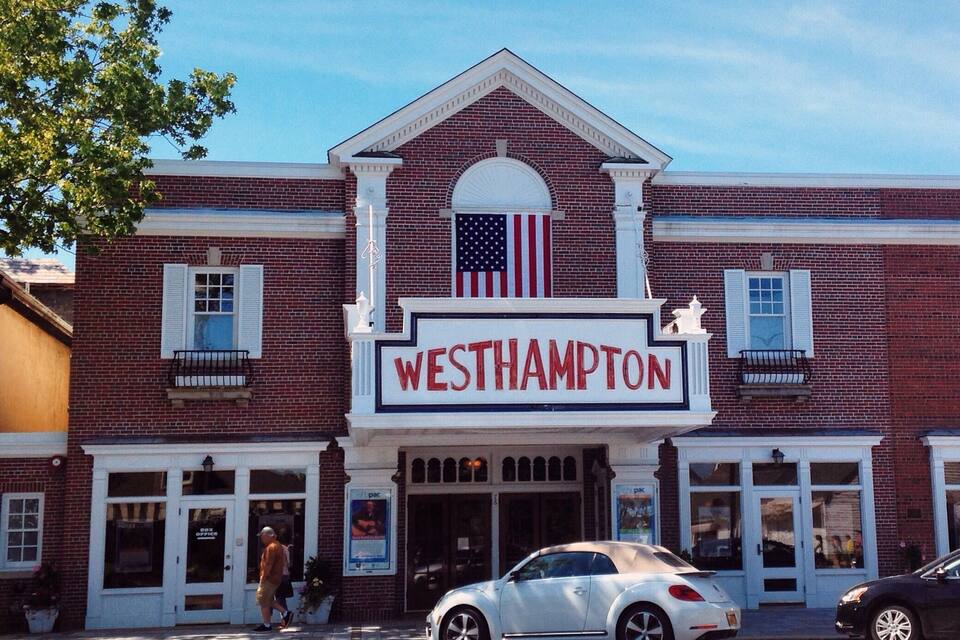 A two-story brick building with a marquee sign reading "WESTHAMPTON" and an American flag above the entrance.