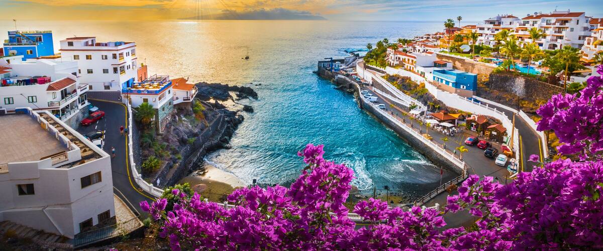 A coastal town with buildings, a rocky shoreline, and a clear sky.