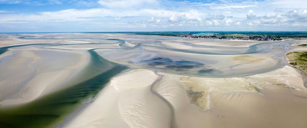 A vast desert landscape with sand dunes and a river meandering through.