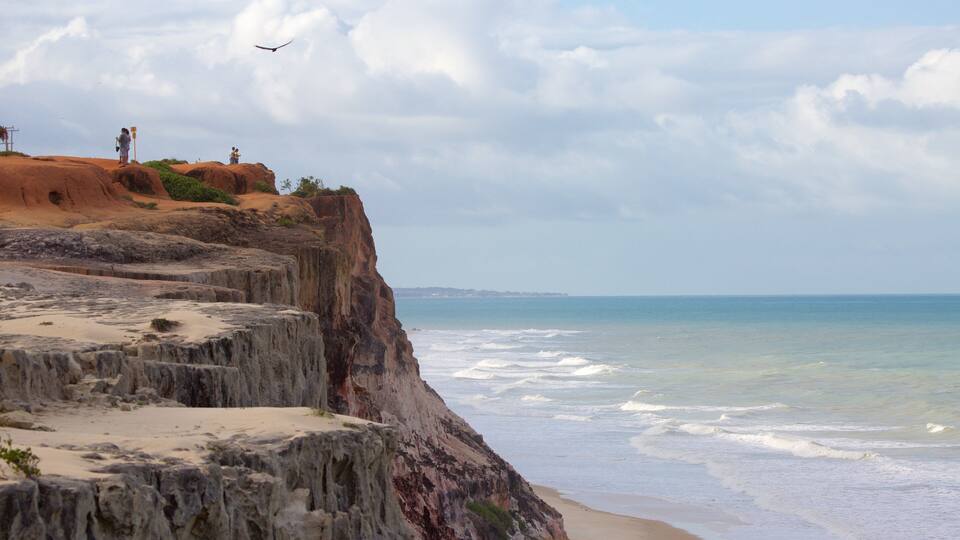 A coastal cliff with a beach and ocean.