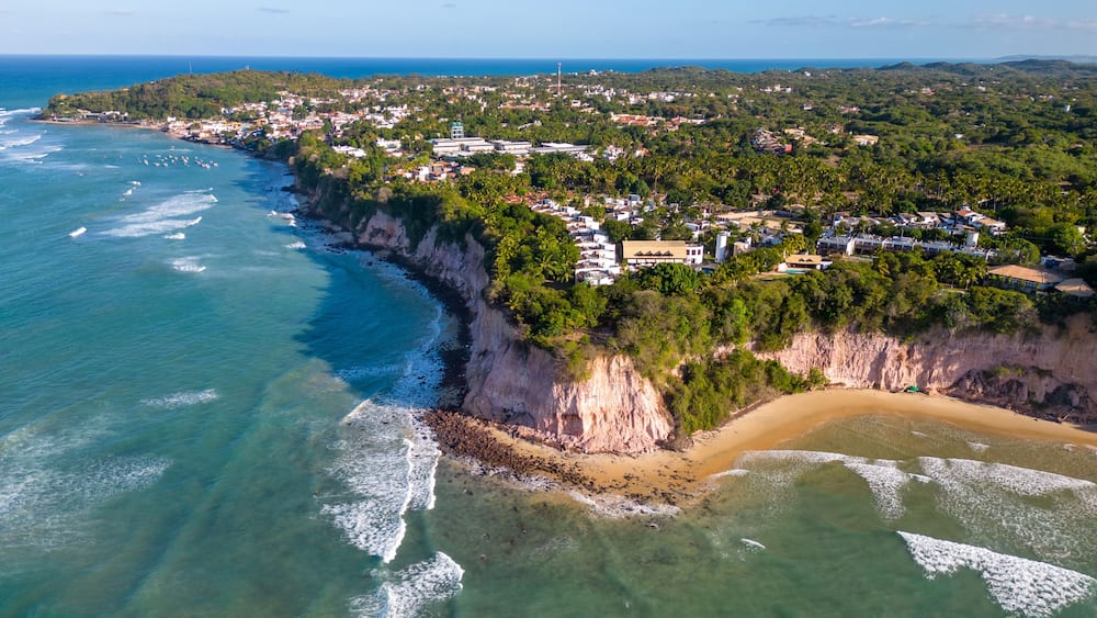 A coastal town with a beach, cliffs, and a clear view of the ocean.
