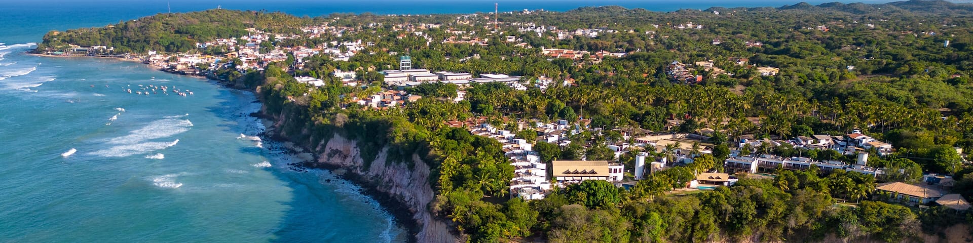 A coastal town with a beach, cliffs, and a clear view of the ocean.