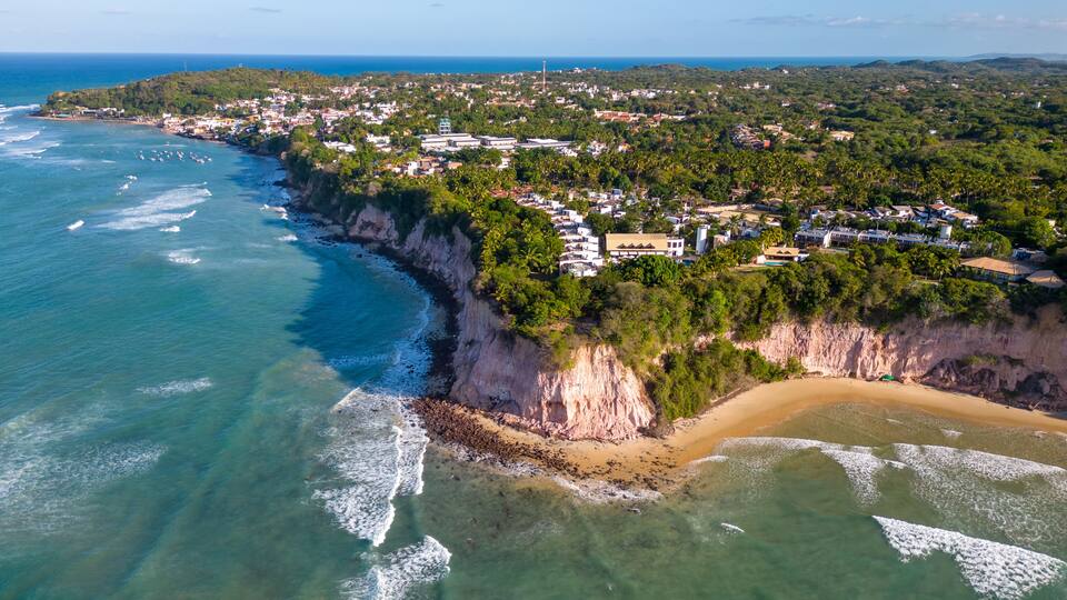 A coastal town with a beach, cliffs, and a clear view of the ocean.