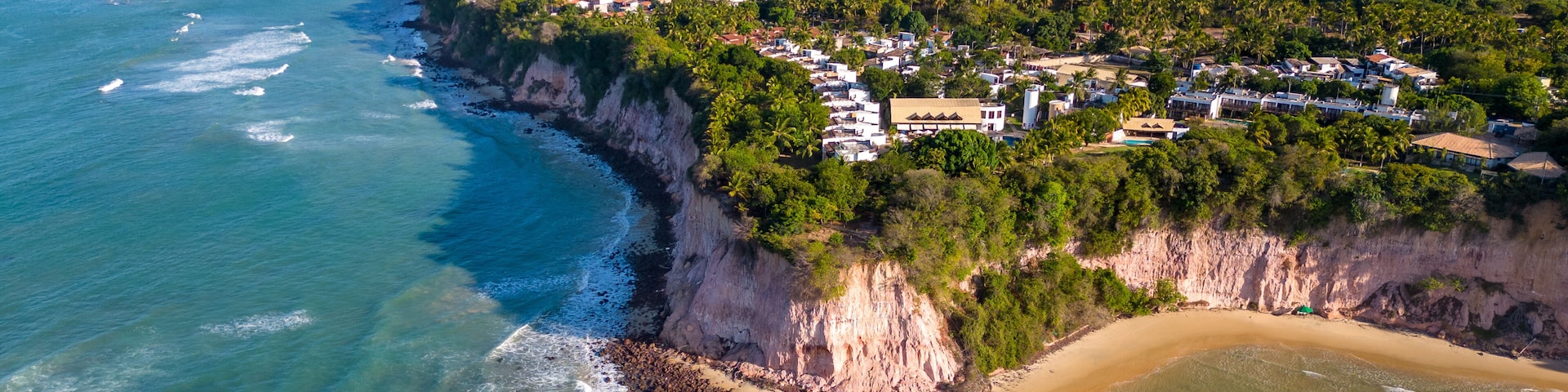 Un pueblo costero con playa, acantilados y una vista despejada del océano.