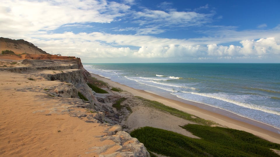 A coastal landscape with a sandy beach, rocky cliffs, and the ocean.