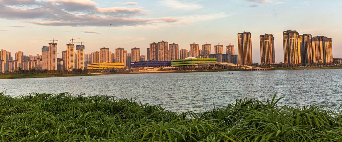 A city skyline with high-rise buildings and a river in the foreground.