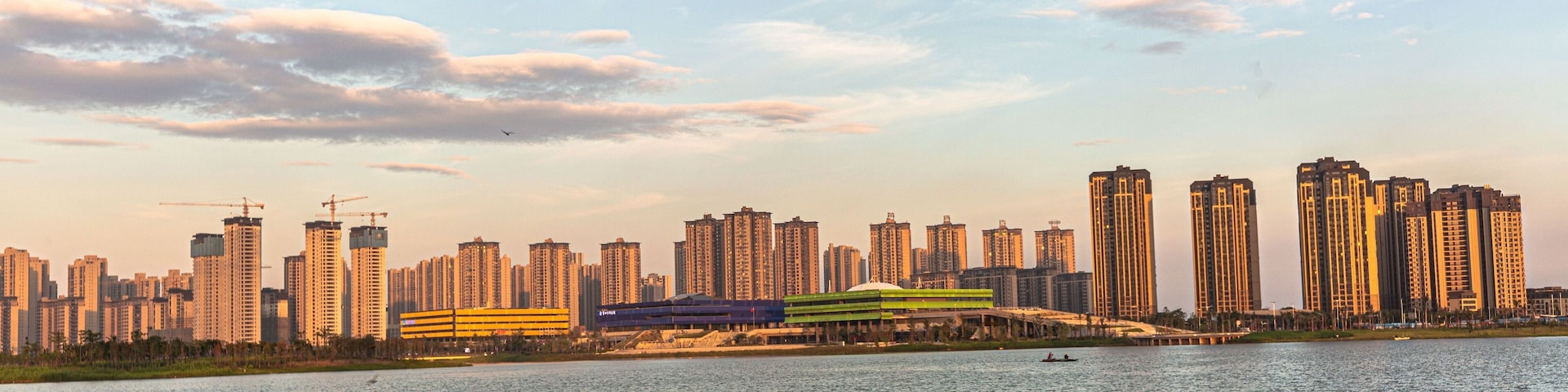 A city skyline with high-rise buildings and a river in the foreground.