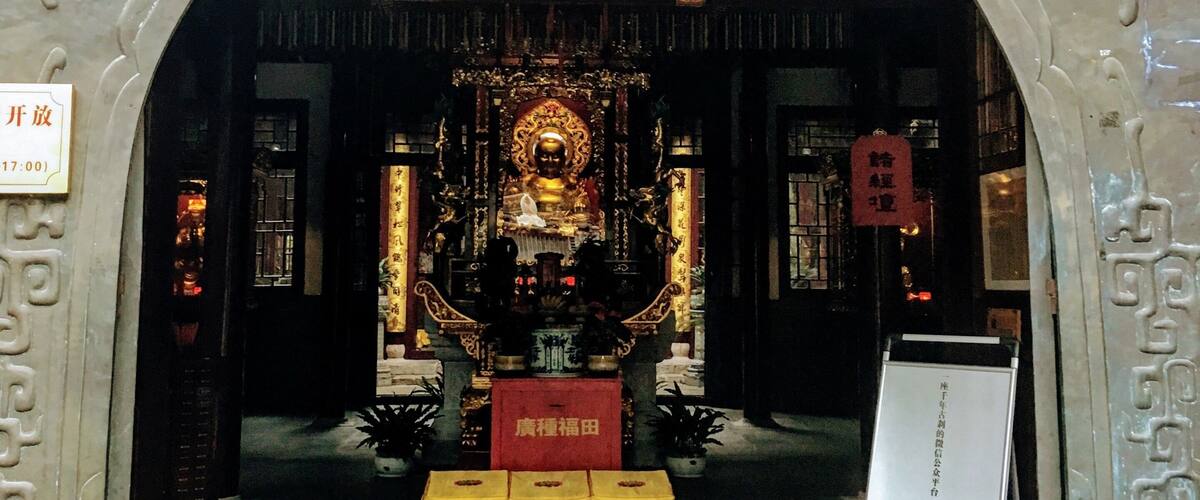 An ornate entrance with traditional Chinese architecture, including a golden statue and intricate carvings.
