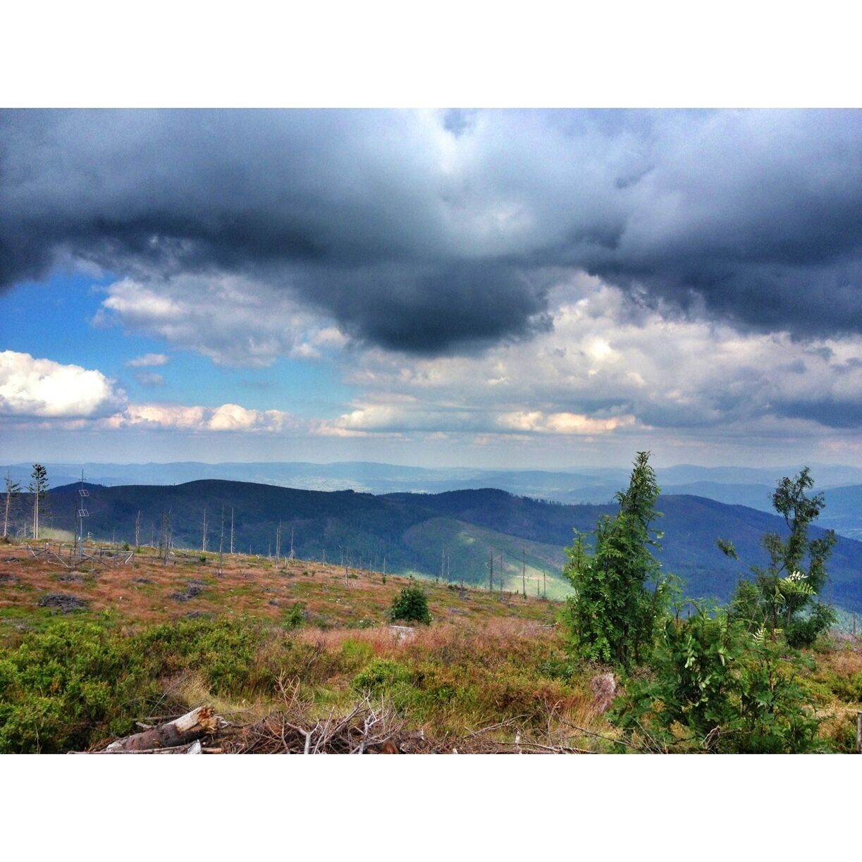 A mountainous landscape with a mix of green vegetation and bare patches, under a partly cloudy sky.