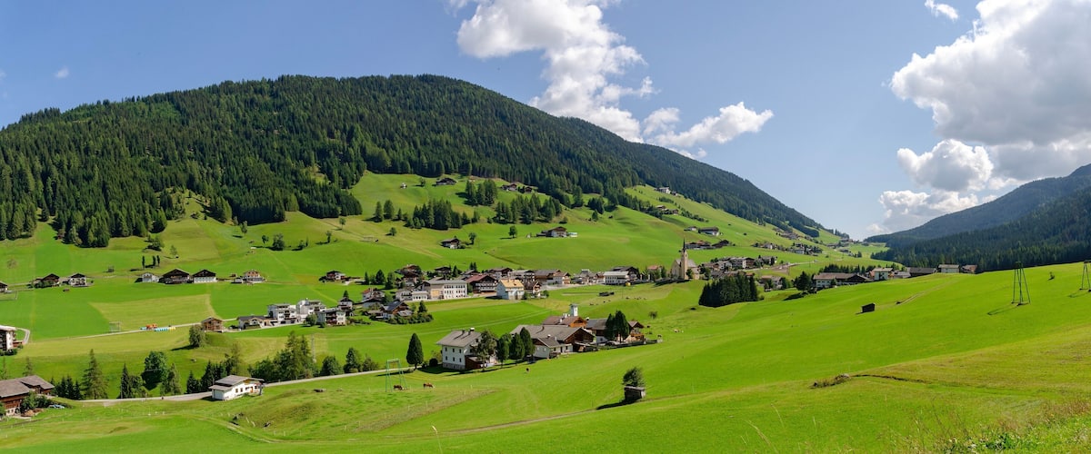 A rural village nestled in a valley with green fields, houses, and a church.