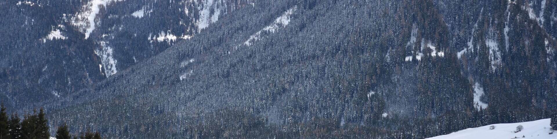 Un pueblo cubierto de nieve con una iglesia y montañas al fondo.