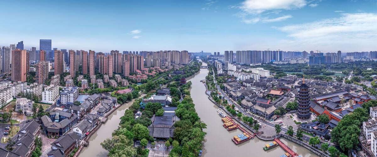 A river running through a city with modern high-rise buildings on one side and traditional architecture on the other.