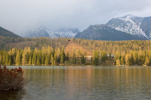 A lodge surrounded by a forest and mountains.