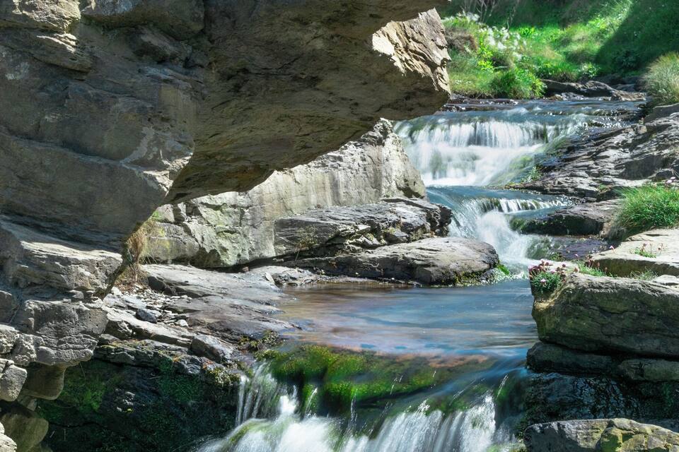 A waterfall cascading over rocks in a mountainous area.