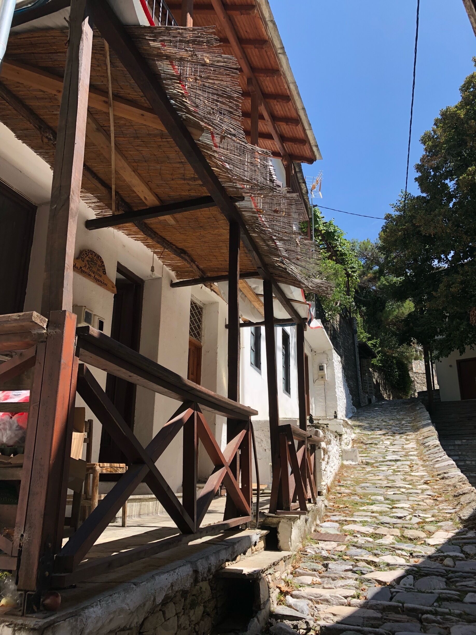 A cobblestone street, wooden balcony railings, and a building with a thatched roof.