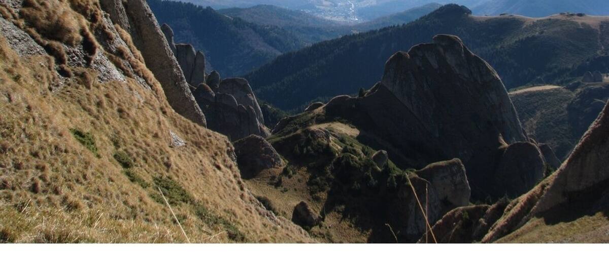 A mountainous landscape with rocky outcrops and a valley in the distance.