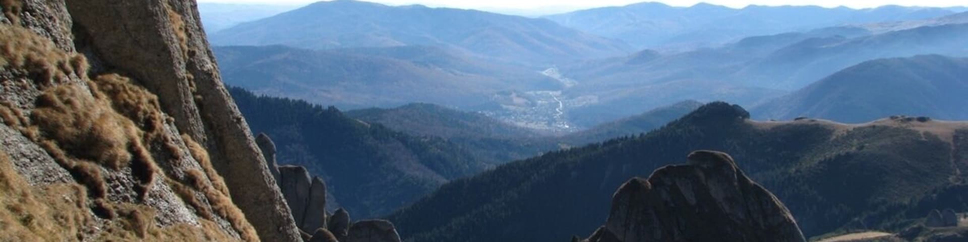 A mountainous landscape with rocky outcrops and a valley in the distance.