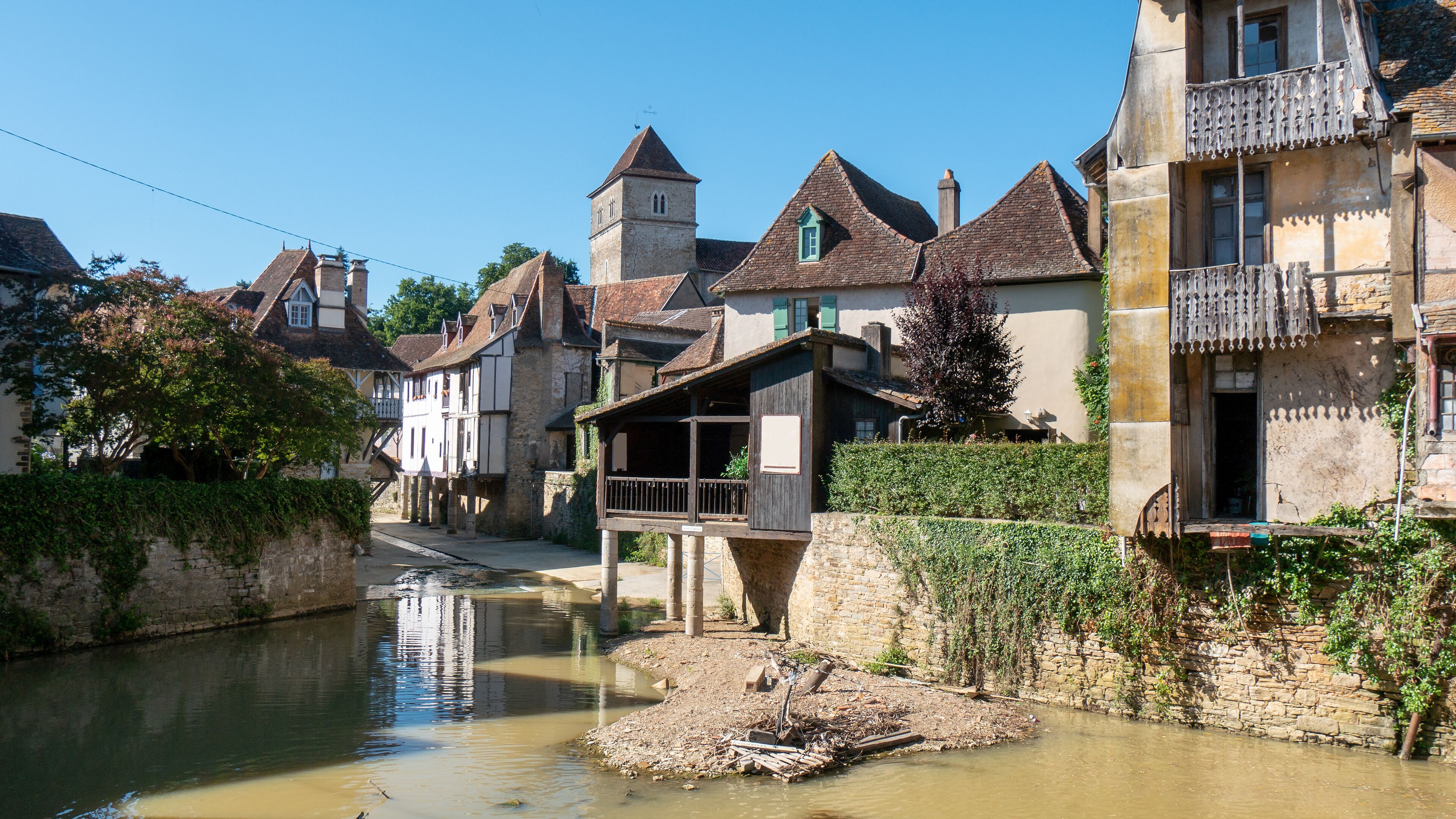 A narrow waterway flanked by historic buildings with steep roofs and a tower.